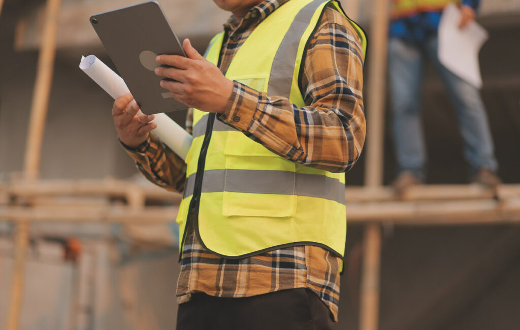 A construction worker is using a tablet to submit his work details for the day